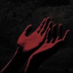 two hands reaching out towards each other in the dark with red light coming from them