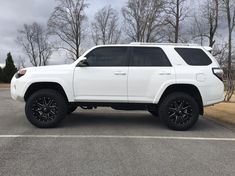 a white toyota 4runner is parked in a parking lot with black wheels and tires