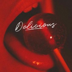 a person holding a red lollipop with the word delicious written in white on it