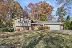 a home in the fall with lots of leaves on the ground and trees around it