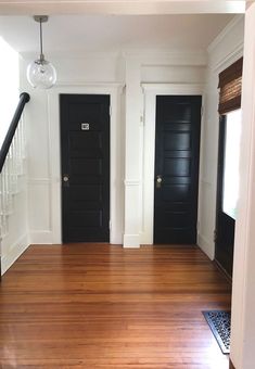 an empty room with two black doors and a wooden floor in front of the door