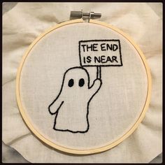 a hand embroidered ghost holding a sign that says the end is near