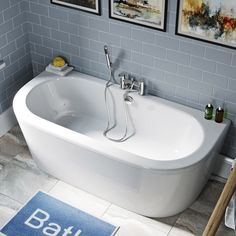 a bath tub sitting in the middle of a bathroom next to pictures on the wall