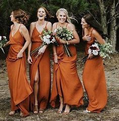 the bridesmaids are all laughing together in their orange dresses and holding bouquets