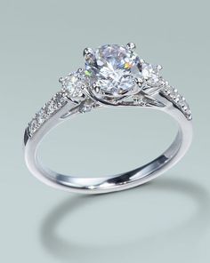 an engagement ring with three stones on the side and one stone in the middle, surrounded by diamonds