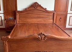 a large wooden bed frame in a room with hardwood flooring and wall paneling