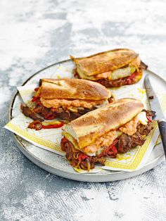 two sandwiches sitting on top of a plate next to a knife