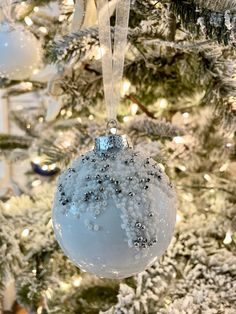 a blue ornament hanging from the side of a christmas tree with snow on it