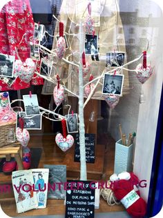 a display window with pictures and hearts hanging from the branches, in front of a tree