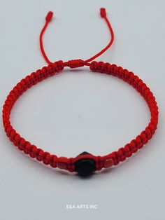 a red string bracelet with a black bead