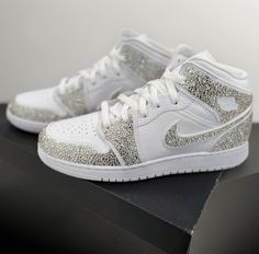 ** PLEASE PLACE YOUR SHOE SIZE IN THE PERSONALIZATION BOX  Where luxury meets style with our custom rhinestoned Nike Air Jordan 1 sneakers, elevate your footwear game with our meticulously crafted designs, blending iconic streetwear with dazzling sophistication. Each pair is meticulously adorned with premium rhinestones, creating a striking statement piece that exudes unparalleled elegance. Whether you're a sneaker aficionado or a fashion-forward trendsetter, our unique creations promise to elevate your look with unmatched flair. Step into the extraordinary and make a lasting impression with our custom rhinestoned Nike Air Jordan 1 sneakers. Luxury High-top Sneakers With Rhinestones, Luxury White Custom Sneakers With Rhinestones, Luxury White Sneakers With Rhinestones, Luxury Silver Custom Sneakers, Iced Out Low-top Sneakers For Streetwear, Luxury Bedazzled Low-top Sneakers, Silver High-top Sneakers With Bling, High-top Bling Sneakers For Streetwear, Sporty Bling Sneakers For Streetwear