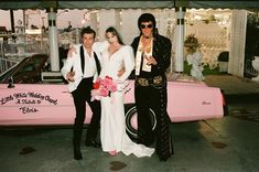 two men and a woman standing in front of a pink car with the bride's name written on it