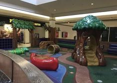 an indoor play area in a mall with slides and trees on the ground, children's playground