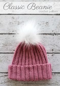 a pink knitted beanie with white pom - pom on top