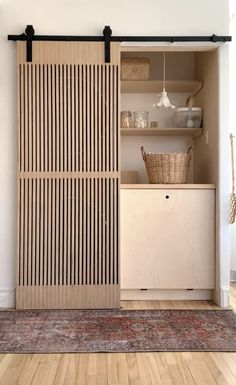 an open closet with shelves and baskets on the door, in front of a rug