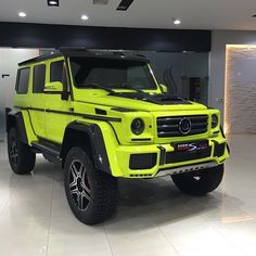 a bright yellow mercedes g - class is parked in a showroom