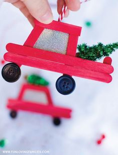 a hand holding a red toy car with a christmas tree on it