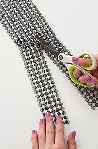 a pair of hands holding scissors and stringing the beading on a piece of fabric