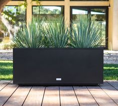 a large planter sitting on top of a wooden deck next to a building with glass windows