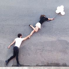 two people are laying on the ground with balloons attached to their backs as if they were falling off