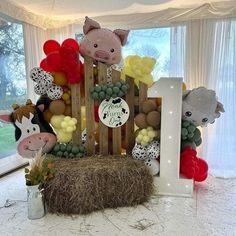 an animal themed birthday party with balloons, hay bales and farm animals on display