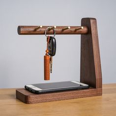 a cell phone and keychain attached to a wooden holder on a table top