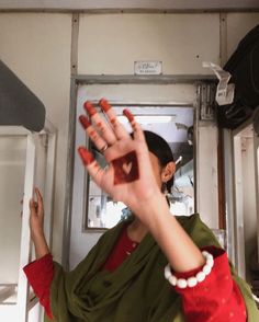 a woman is holding her hand up in the air while wearing a green shirt and red top