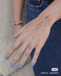 a woman's hand with a star tattoo on her left wrist and blue nail polish