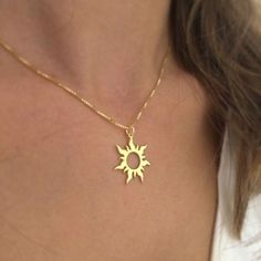 a woman wearing a gold necklace with the sun on it's back and bottom