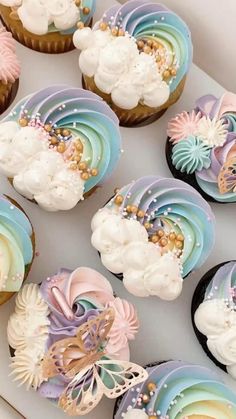 cupcakes decorated with pastel colors and flowers are on a white tray next to each other