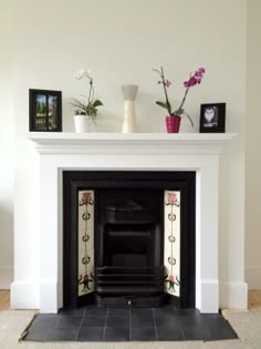 a white fireplace with flowers and pictures on the mantle