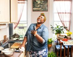 a woman is laughing while cooking in the kitchen