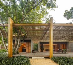 an outdoor covered patio area with wooden posts and plants on the ground, surrounded by greenery