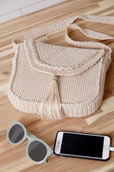 a purse, sunglasses and cell phone on a wooden floor