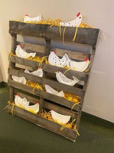 a wooden pallet filled with chicken shoes and straw on top of green carpeted flooring