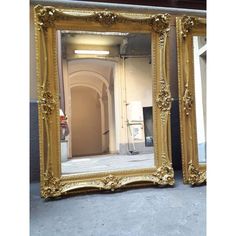 a large gold framed mirror sitting on top of a cement floor next to a doorway