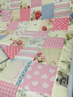 a pink and white patchwork quilt on a bed with flowers in the middle,