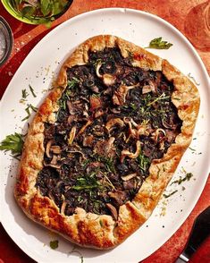 a pizza on a plate with mushrooms and herbs