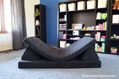 a large black sculpture in the middle of a room with blue walls and shelves filled with toys