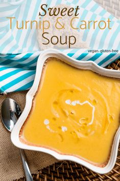 a white bowl filled with carrot soup on top of a woven table cloth next to a spoon