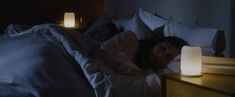 two people sleeping in bed with the night light turned on and one person laying down