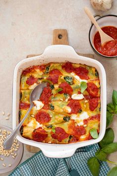 a casserole dish with tomatoes, mozzarella and spinach in it