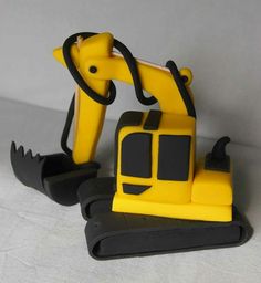 a yellow and black toy excavator sitting on top of a white surface