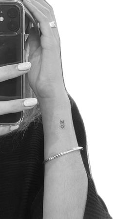 a woman with a tiny butterfly tattoo on her left wrist is taking a selfie