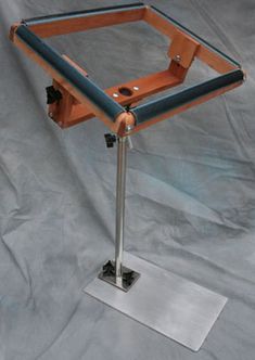 a wooden table with metal legs and a square frame on it's base, against a gray background