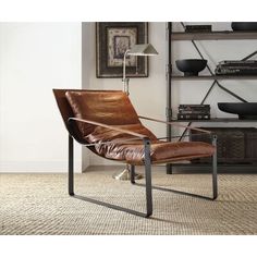 a brown leather chair sitting on top of a carpeted floor next to a book shelf