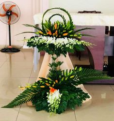 a floral arrangement is displayed on the floor in front of a fan and other decorations