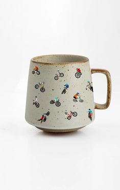 a ceramic mug with people riding bicycles on it's side and inside the cup