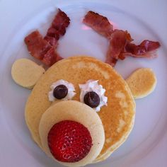 pancakes with strawberries and bacon on them are shaped like a reindeer's face