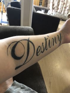 a person's arm with the word destiny written on it in cursive writing